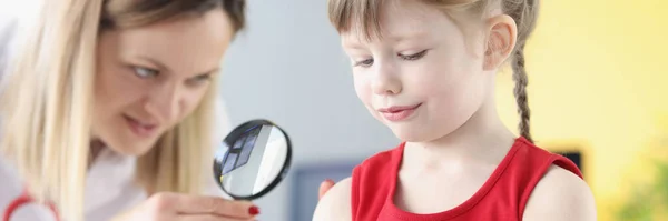 Hautarzt untersucht kleine Mädchenhand durch Lupe — Stockfoto