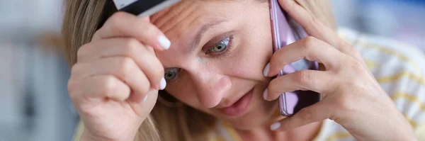 Upset woman in stress holds bank card and talks on phone — Stock Photo, Image