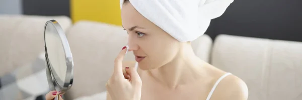 Lachende mooie dame brengt huidverzorgingscrème aan op het gezicht terwijl ze in de spiegel kijkt — Stockfoto