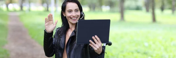 Behinderte Frau mit Kopfhörer, Mikrofon und Laptop arbeitet im Rollstuhl im Park — Stockfoto