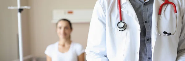 Doktor se stetoskopem a dokumenty v rukou stojící v nemocnici s pacientkou detailní záběr — Stock fotografie
