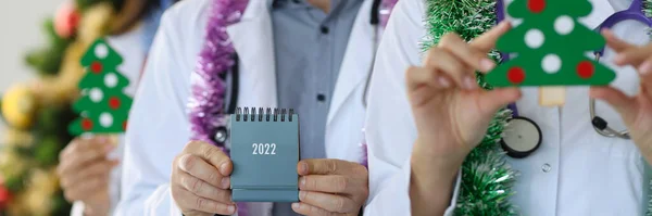 Gruppo di medici in possesso di calendario per il 2022 e albero di Natale in primo piano clinica — Foto Stock