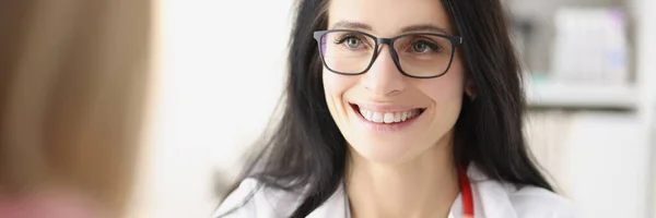 Glimlachende vrouwelijke arts geeft visitekaartje aan patiënt bij de receptie in kliniek — Stockfoto