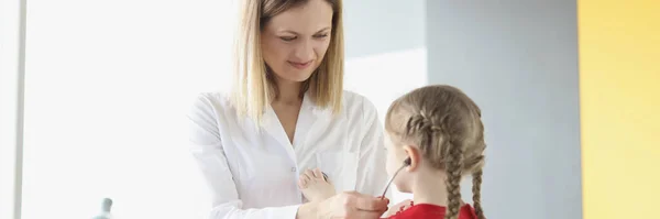 Лікар-педіатр кладе стетоскоп на маленьку дівчинку в клініку — стокове фото