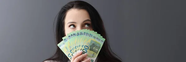 Νεαρή σκεπτική γυναίκα που κρατάει πολλά χαρτονομίσματα του ευρώ μπροστά της — Φωτογραφία Αρχείου