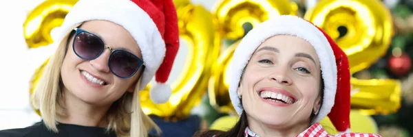 Portret van twee jonge lachende vrouwen tegen de achtergrond van kerstboom en nummers 2022 — Stockfoto