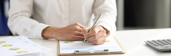 Affärskvinna håller penna och gör justeringar i rapporten om finansiella indikatorer i diagram — Stockfoto