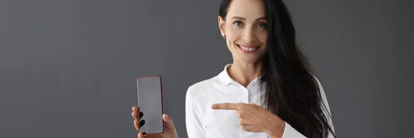 Retrato sonriente de una mujer sosteniendo un smartphone en la mano —  Fotos de Stock