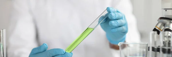 Cientista em luvas de proteção detém tubo de ensaio com fecho líquido verde — Fotografia de Stock
