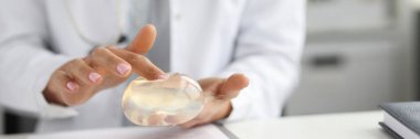 Klinikte göğüs silikonu tutan doktor.