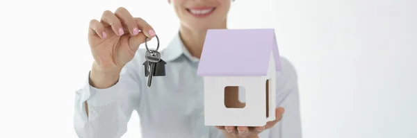 Sorrindo agente feminina segurando pequena casa e chaves — Fotografia de Stock