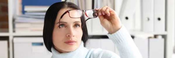 Жінка знімається і дивиться на окуляри, сидячи на робочому місці — стокове фото