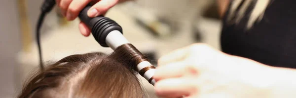 Парикмахерские руки делают волосы с щипцами для завивки волос — стоковое фото