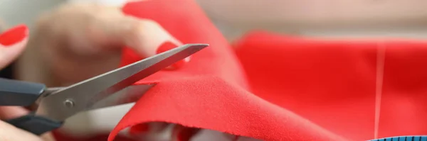 Manos femeninas cortadas paño rojo con tijeras —  Fotos de Stock