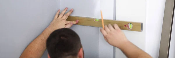 Man builder markerar linjen på väggen — Stockfoto