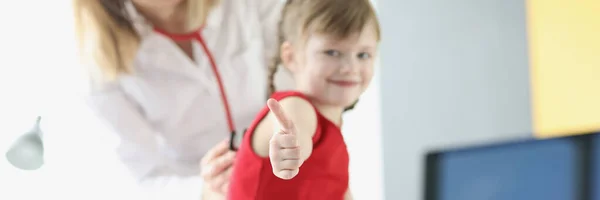 Mała dziewczynka u pediatry trzyma kciuki w górze. — Zdjęcie stockowe