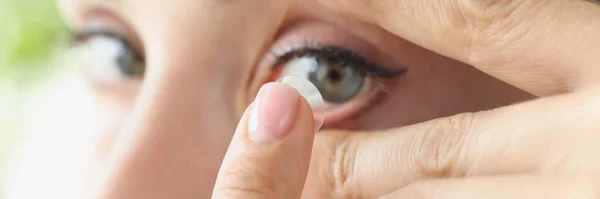Vrouw zet op zacht contact lens over ogen closeup — Stockfoto