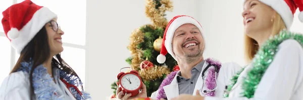 Lachende team van artsen in rode petten tegen de achtergrond van de kerstboom — Stockfoto