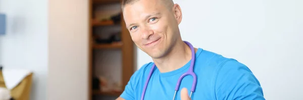 Retrato de jovem sorridente médico masculino segurando polegares para cima — Fotografia de Stock