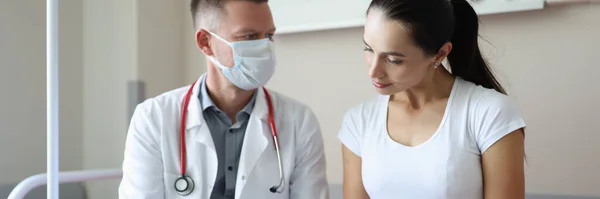 의료용 마스크를 착용하고 있는 의사는 입원 해 있는 환자와 의사소통을 한다 — 스톡 사진