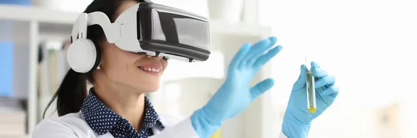 Женщина-химик в очках виртуальной реальности держит пробирку в лаборатории — стоковое фото