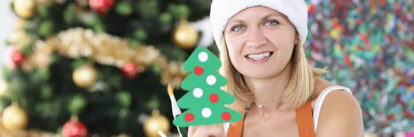 Mujer artista en santa hat sosteniendo juguete árbol de navidad y pinceles —  Fotos de Stock