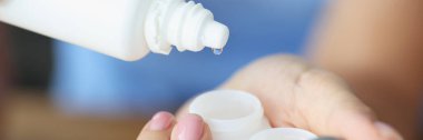 Kadın, plastik kaplara mercek sıvısı döküyor.
