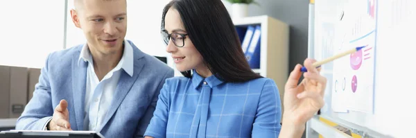 Joven hombre y mujer mirando la pantalla de la tableta digital y el estudio de la información en pizarra —  Fotos de Stock