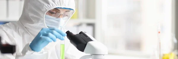 Cientista químico em terno de proteção segurando tubo de ensaio com líquido verde em laboratório — Fotografia de Stock