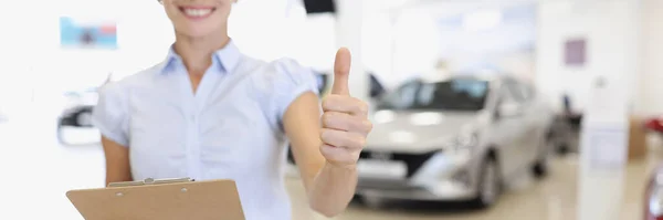 Менеджер з продажу автомобілів тримає великі пальці в автосалоні — стокове фото