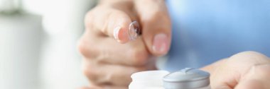 Kadın parmağı plastik kutudan kontak lensleri çekiyor.