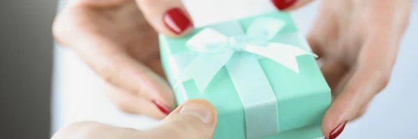 En las manos de la mujer es pequeña caja de regalo de color turquesa con arco —  Fotos de Stock