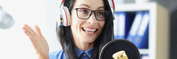 Жінка-ведуча радіо з навушниками, що розмовляють мікрофоном в студії — стокове фото