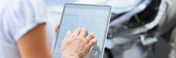 Agent-Fahrer füllt Versicherungsanspruch auf digitalem Tablet vor dem Hintergrund kaputter Auto-Nahaufnahme aus — Stockfoto