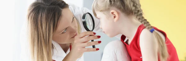 Augenarzt führt medizinische Untersuchung des Mädchenauges durch Lupe durch — Stockfoto