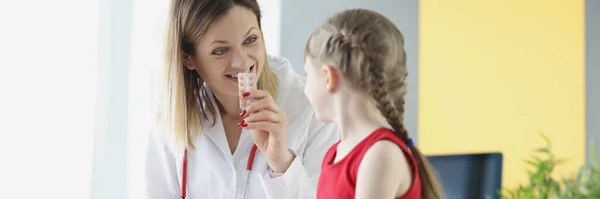 Lekarz pokazuje małą dziewczynkę blister z lekami w klinice — Zdjęcie stockowe