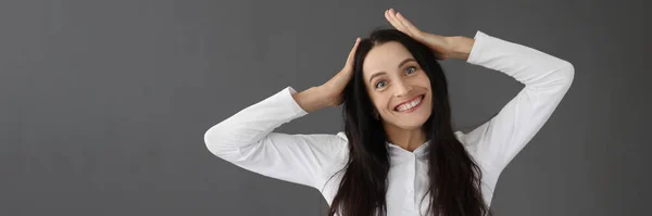 Jong glimlachende vrouw houden haar hoofd op grijze achtergrond — Stockfoto