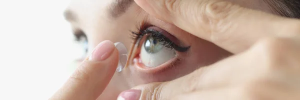 Mujer joven insertando lentes de contacto en su ojo con el dedo en primer plano — Foto de Stock