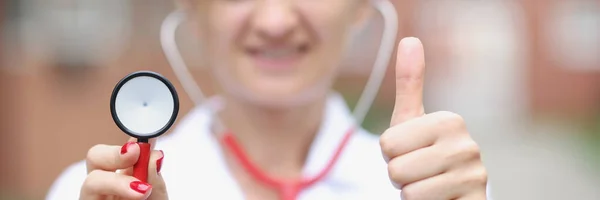 Woman doctor showing thumb up and head of stethoscope closeup — Stock Photo, Image