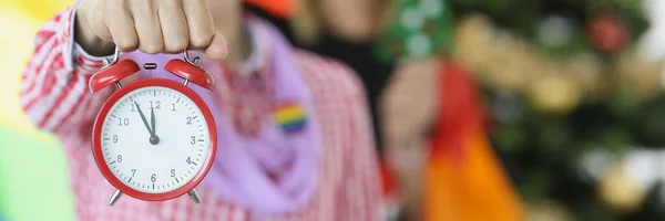 Kilka kobiet z flagą lgbt trzymając czerwony budzik w pobliżu nowego roku drzewo zbliżenie — Zdjęcie stockowe