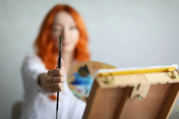 Una mujer sostiene un pincel con una paleta para pinturas —  Fotos de Stock
