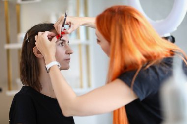 Usta, kalemli bir kadına kaş çizer.