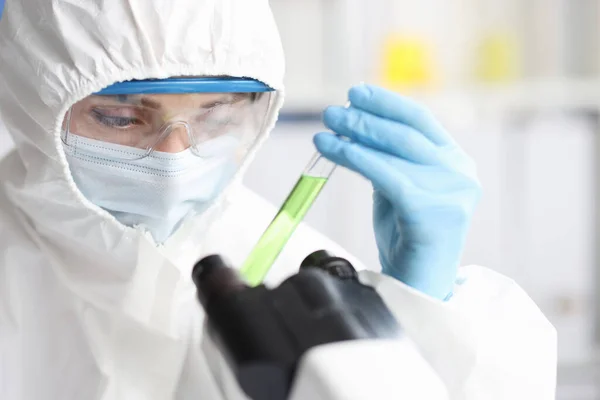 Cientista em terno protetor detém tubo de ensaio com líquido venenoso — Fotografia de Stock