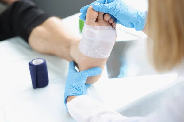 Orvos kéz megérinti és megvizsgálja a sebet a lábon — Stock Fotó