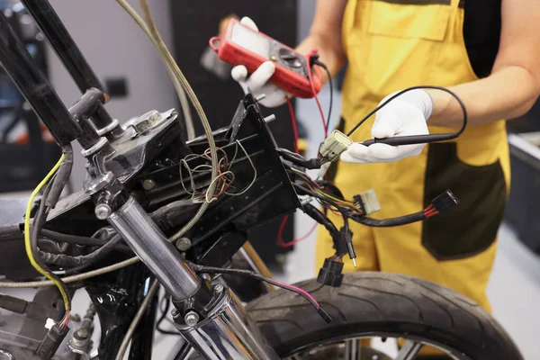 Çoklu metre kontrolü kullanan tamirci voltaj seviyesi motosiklet bataryası garajı — Stok fotoğraf