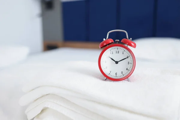 침대에 있는 수건으로 아침이나 저녁 10 시까지 시계를 감는다 — 스톡 사진