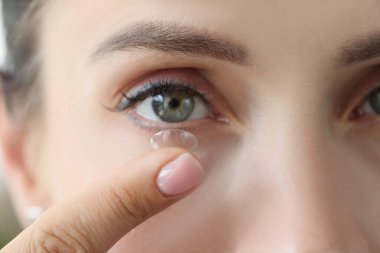 Bir kadın gözüne kontak lens yerleştiriyor, yakın plan.