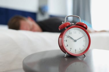 Yatak odasındaki masada kırmızı bir çalar saat duruyor.