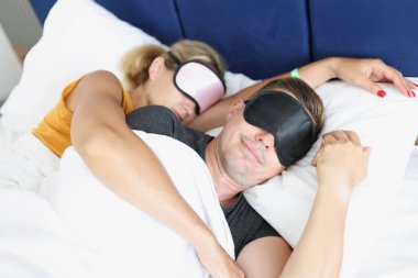 Uyuyan mutlu çift yüzlerinde uyku maskeleriyle sarılıyorlar.