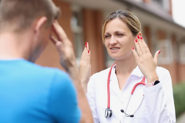 Een vrouwelijke arts spreekt met een man op straat, close-up — Stockfoto